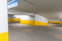 an empty parking garage with yellow painted walls and flooring and an exit sign in the foreground