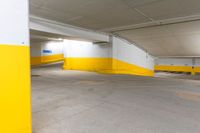 an empty parking garage with yellow painted walls and flooring and an exit sign in the foreground