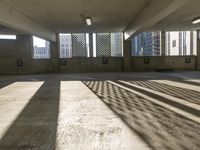 an empty parking garage is filled with parking meters and fire hydrants, some casting shadows