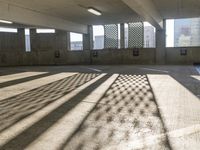 an empty parking garage is filled with parking meters and fire hydrants, some casting shadows