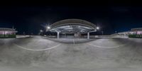 an empty parking garage at night with a skateboarder doing tricks on the ramp