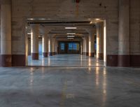 an empty parking garage with lots of lights and a long hallway to the outside area