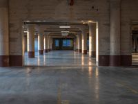 an empty parking garage with lots of lights and a long hallway to the outside area