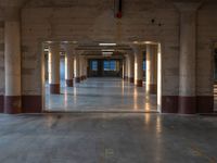 an empty parking garage with lots of lights and a long hallway to the outside area