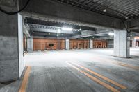 an empty parking garage with yellow line paint on the floor and black steel columns,