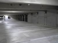 empty parking garage floor in a large space with graffiti on it's floor and roundel windows above