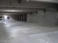 empty parking garage floor in a large space with graffiti on it's floor and roundel windows above