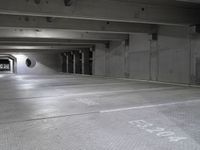 empty parking garage floor in a large space with graffiti on it's floor and roundel windows above