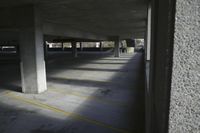 an empty parking garage with several parking spaces and yellow lines on the ground the area is grey in color