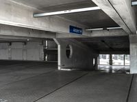 an empty parking garage filled with parking meters and one blue arrow pointing to the left