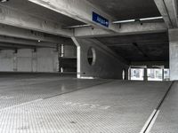 an empty parking garage filled with parking meters and one blue arrow pointing to the left