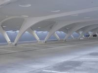 an empty parking garage with lots of columns and cars parked on the road next to it