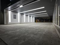 an empty parking garage with a sign in the corner and lights on each side of the wall