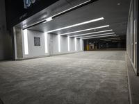 an empty parking garage with a sign in the corner and lights on each side of the wall