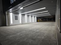 an empty parking garage with a sign in the corner and lights on each side of the wall