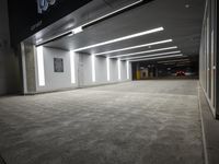 an empty parking garage with a sign in the corner and lights on each side of the wall