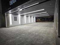 an empty parking garage with a sign in the corner and lights on each side of the wall