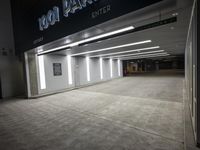 an empty parking garage with a sign in the corner and lights on each side of the wall