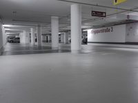 the empty parking garage is full of empty cars or trucks at night time in a white room