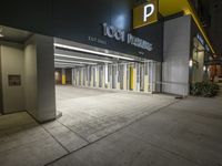 an empty parking garage at night with light on the doors and parking spaces on either side