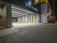 an empty parking garage at night with light on the doors and parking spaces on either side