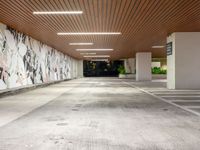 an empty parking garage has painted walls and lights above the concrete flooring of it