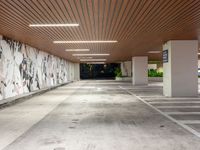 an empty parking garage has painted walls and lights above the concrete flooring of it