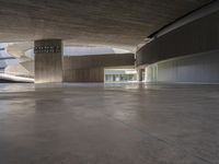 an empty parking garage with light reflecting on it and concrete floors with concrete accents and a round roof