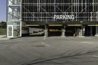 a parking garage with a sign for the parking garage at an empty parking lot between two tall buildings