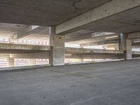 empty parking garage area with no doors and only two floor spaces with one large building behind