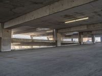 empty parking garage area with no doors and only two floor spaces with one large building behind