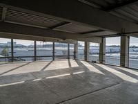 an empty parking garage with a long walkway leading to it's door and a view of a waterway