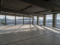 an empty parking garage with a long walkway leading to it's door and a view of a waterway