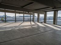 an empty parking garage with a long walkway leading to it's door and a view of a waterway