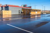 an empty parking lot next to a shopping center on a street corner with a sky background