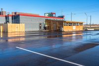 an empty parking lot next to a shopping center on a street corner with a sky background