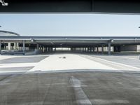 a long empty parking lot near an airport where airplanes are lined up, all parked and empty