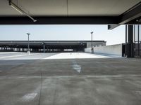 a long empty parking lot near an airport where airplanes are lined up, all parked and empty