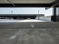 a long empty parking lot near an airport where airplanes are lined up, all parked and empty