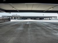 a long empty parking lot near an airport where airplanes are lined up, all parked and empty