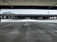 a long empty parking lot near an airport where airplanes are lined up, all parked and empty