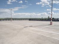 a empty parking lot next to an airport with a sky background and some white and orange stripes