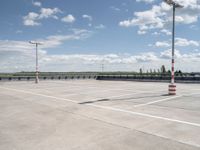 a empty parking lot next to an airport with a sky background and some white and orange stripes