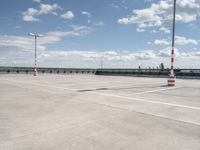 a empty parking lot next to an airport with a sky background and some white and orange stripes