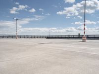 a empty parking lot next to an airport with a sky background and some white and orange stripes