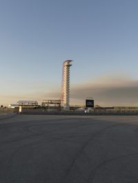 an empty parking lot at a parking space with an airport and the tower in the distance