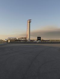 an empty parking lot at a parking space with an airport and the tower in the distance