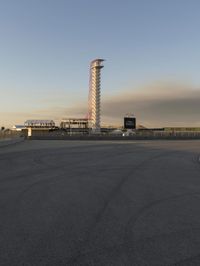 an empty parking lot at a parking space with an airport and the tower in the distance