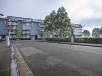 an empty parking lot in front of large apartment buildings, and a gated sidewalk