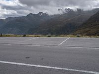 an empty parking lot on the side of the mountain with mountains and fog covered mountains around it